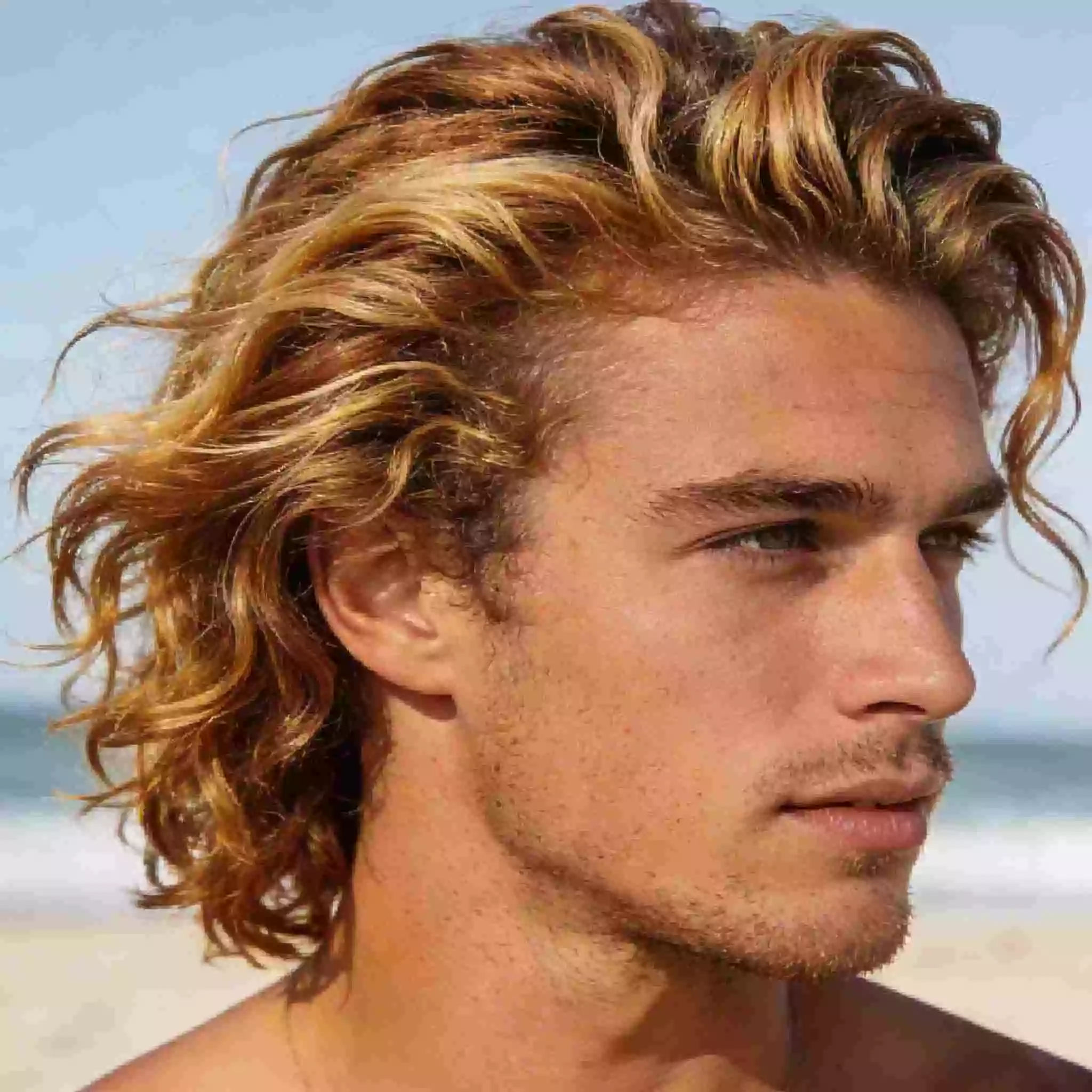 medium surfer hair for men with a bro flow brushed back and loose waves